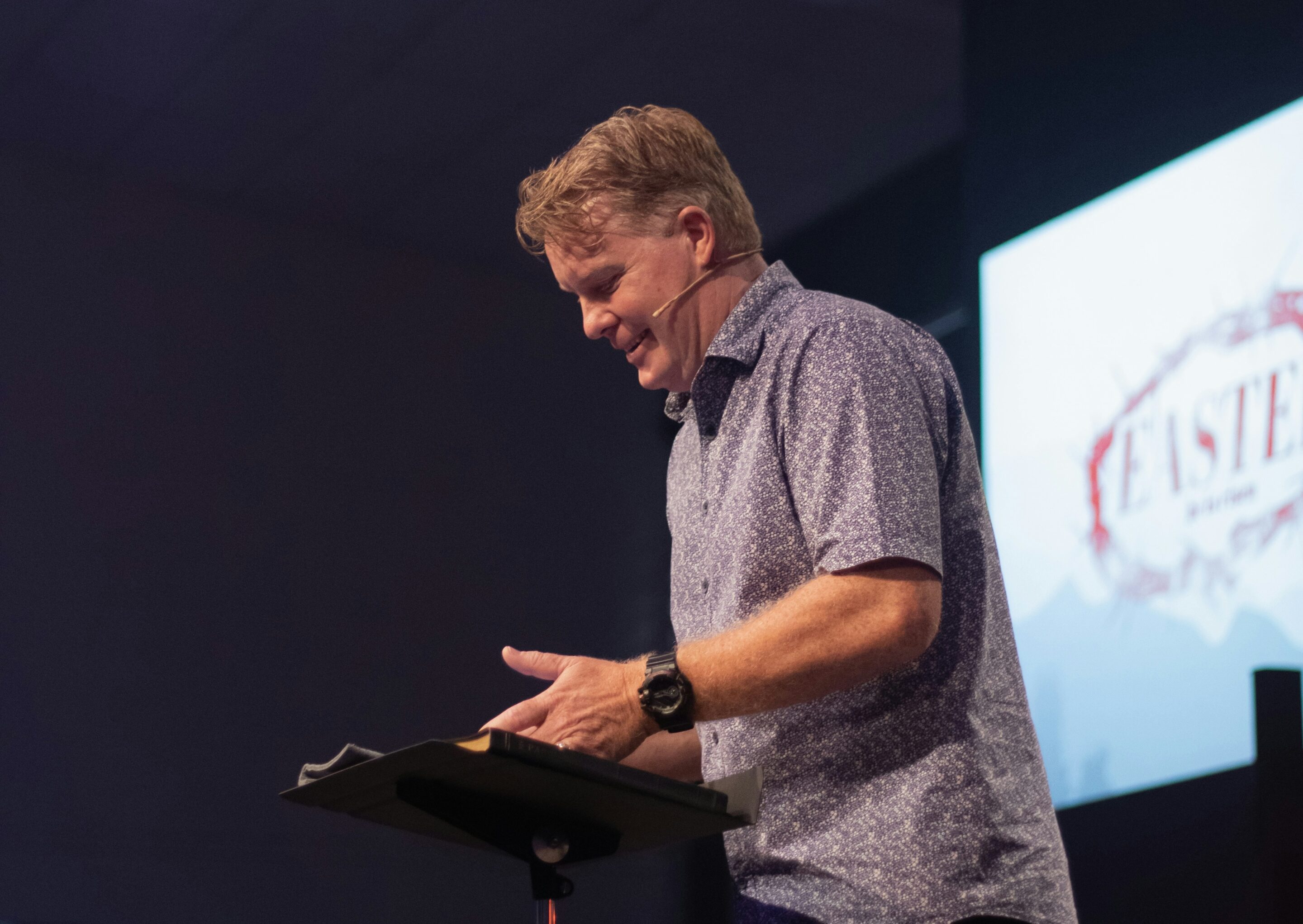 pastor speaking in front of screen displaying from church presentation software